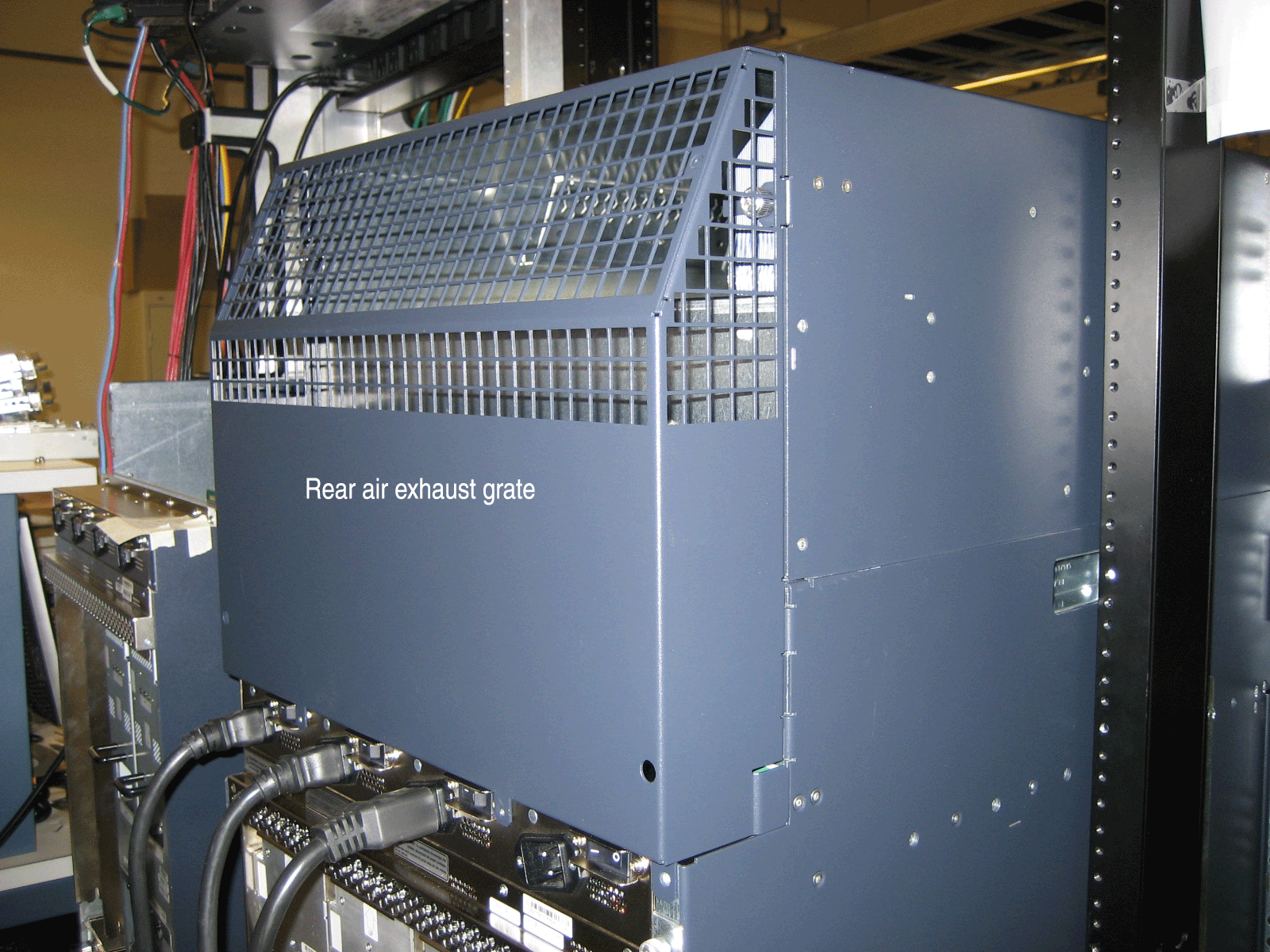Server or network device in rack with rear air exhaust grate and multiple connected cables for ventilation and network setup.