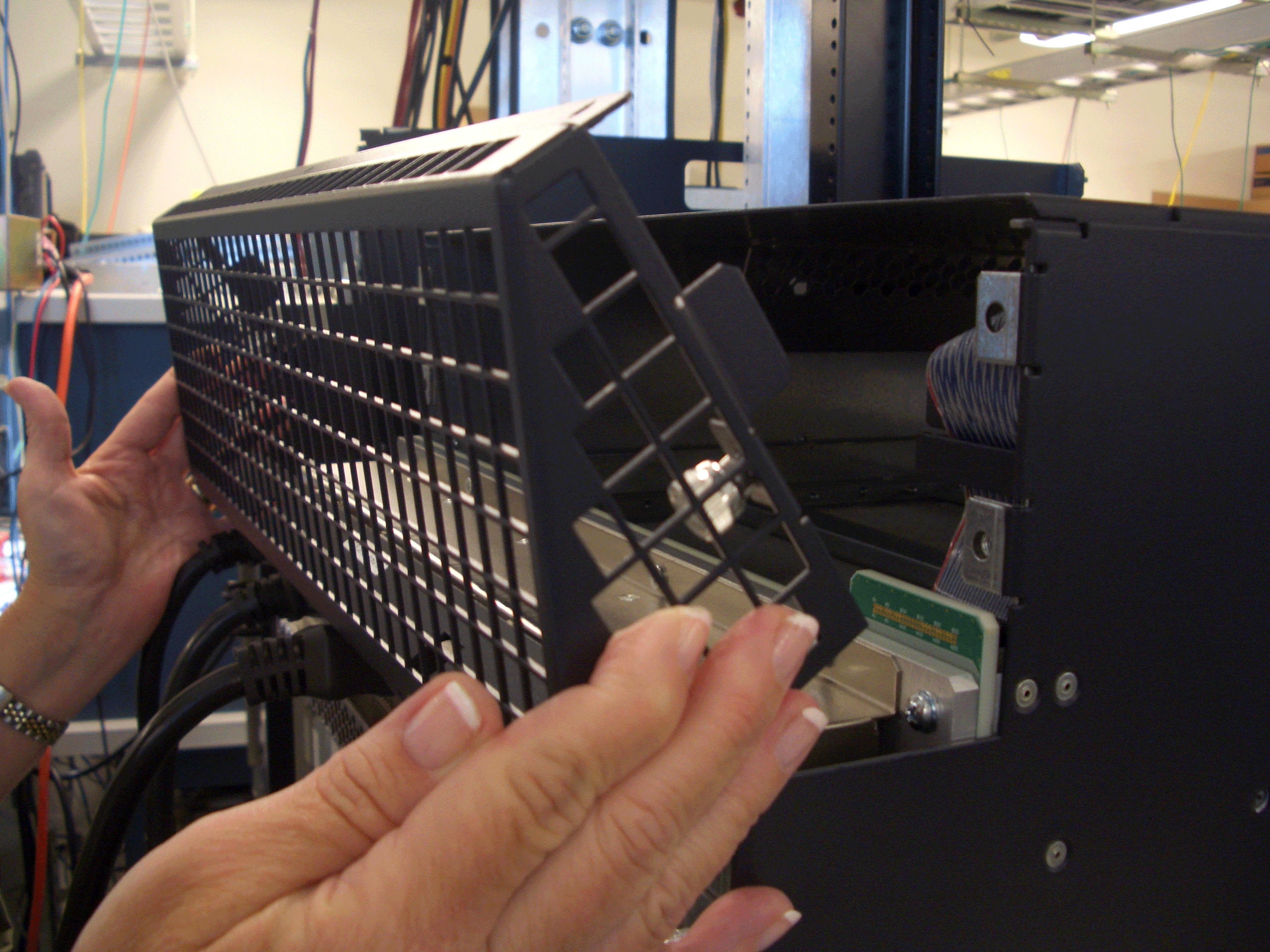 Technician working on server equipment in a data center, adjusting a vented panel to ensure airflow.