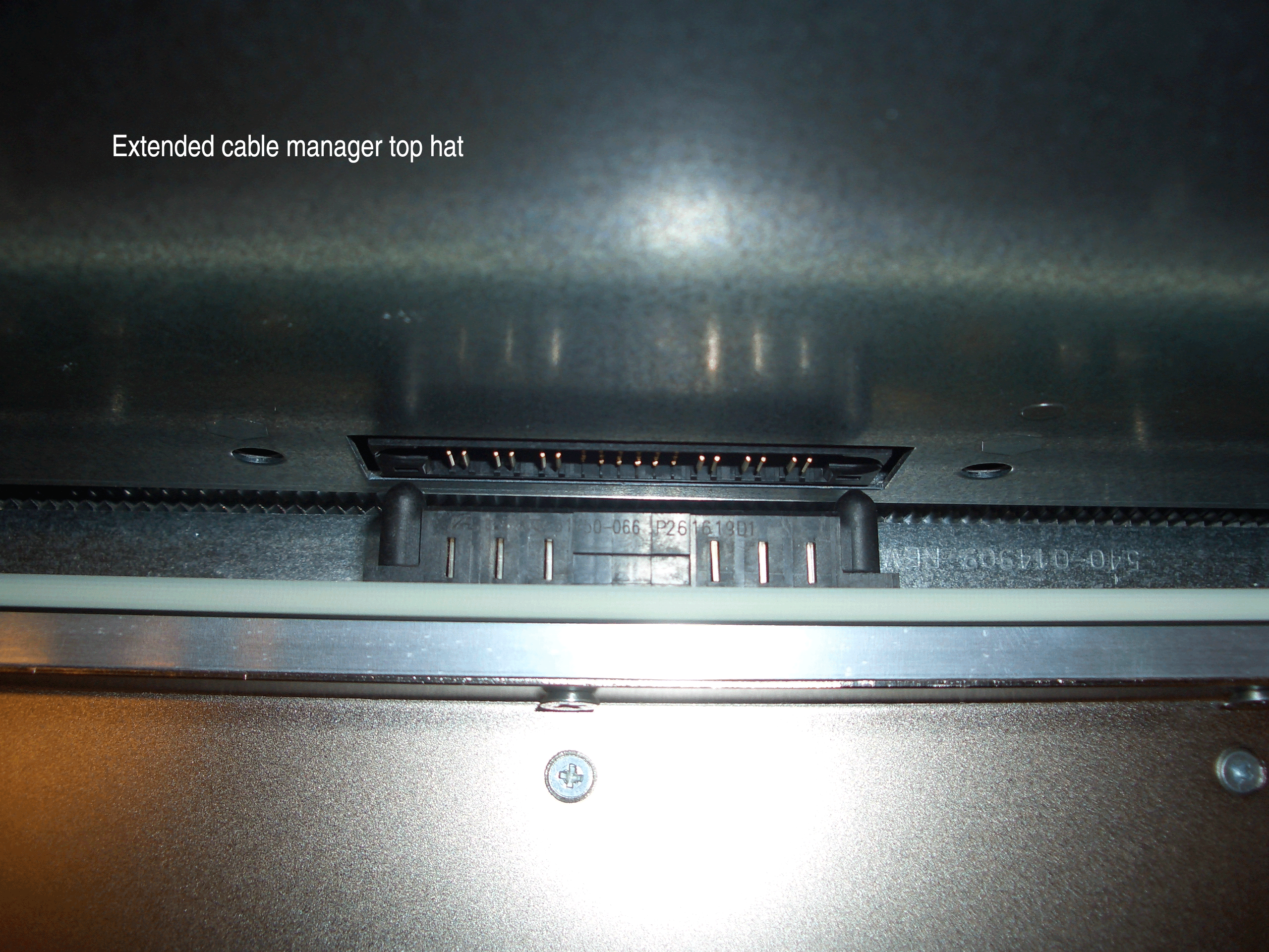 Close-up of a multi-pin connector on electronic equipment with text: Extended cable manager top hat.