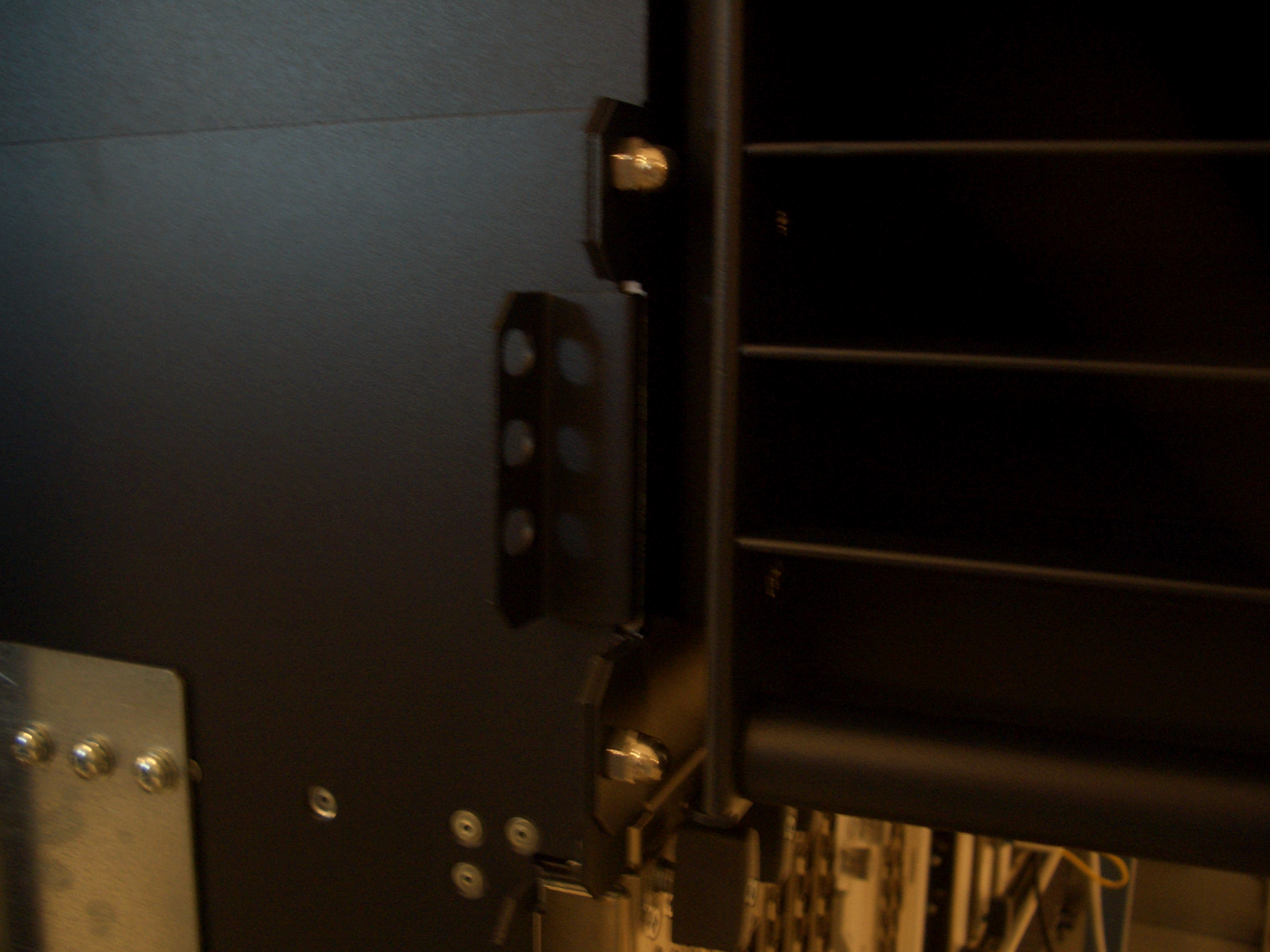 Close-up of industrial equipment with metal components, screws, and horizontal slats, suggesting server rack or computer hardware.