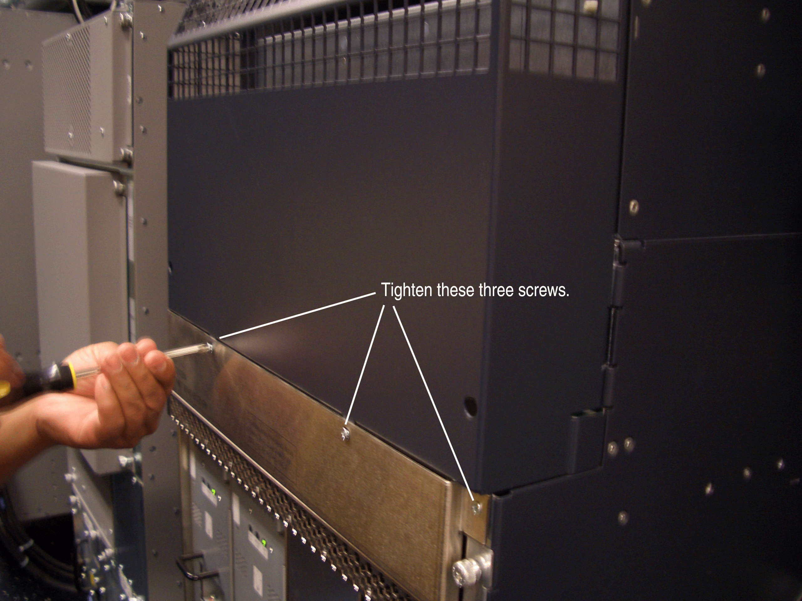 Person tightening screws on equipment with text overlay: Tighten these three screws.