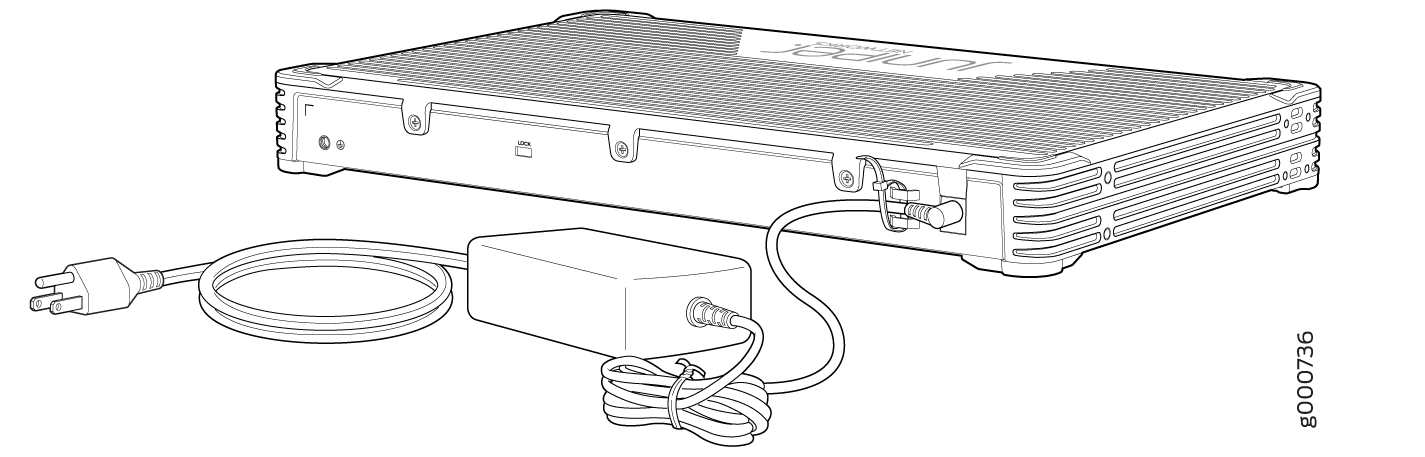 Juniper Networks device with power adapter connected, featuring side ventilation slots and a front panel LOCK label.