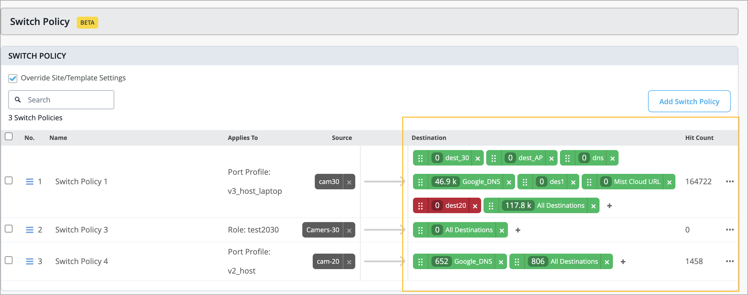 User interface for managing Switch Policies in a network system, showing a list of policies with details like number, name, configurations, applies to, source, destination, and hit count. Features include a checkbox to override settings, a search bar to filter policies, an expanded policy showing detailed rules, and an Add Switch Policy button for creating new policies.